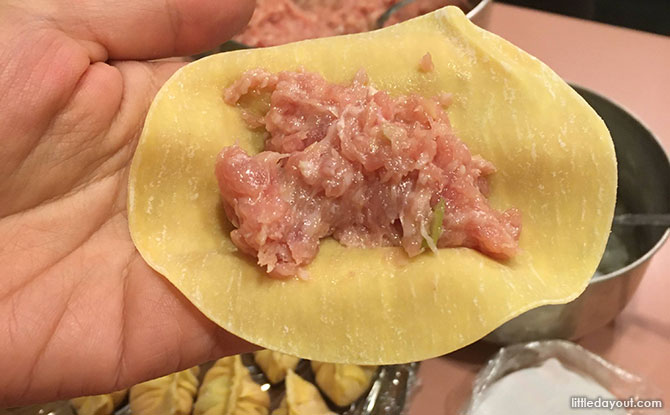 Hold a piece of the wrapper on your palm, scoop 2 tsp of pork mixture on the centre, and add a piece of shrimp bite on it. 