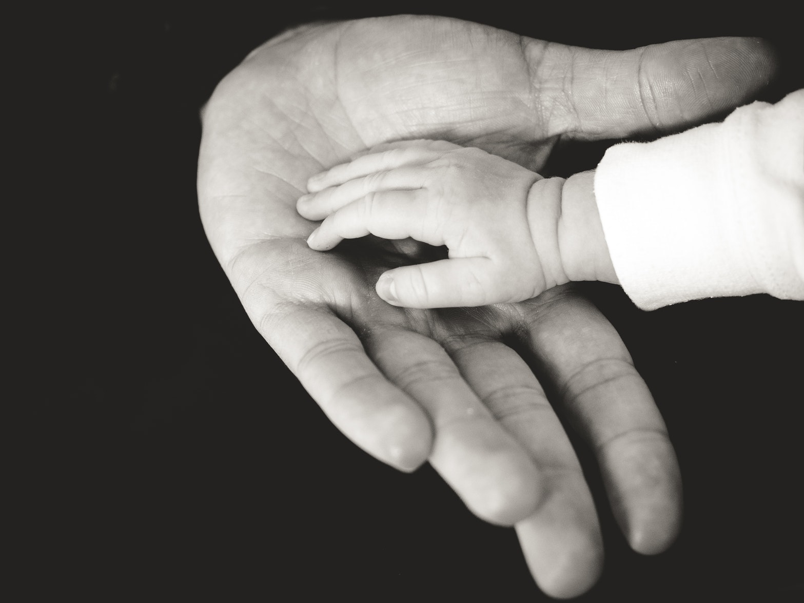 Father and baby touching hands 