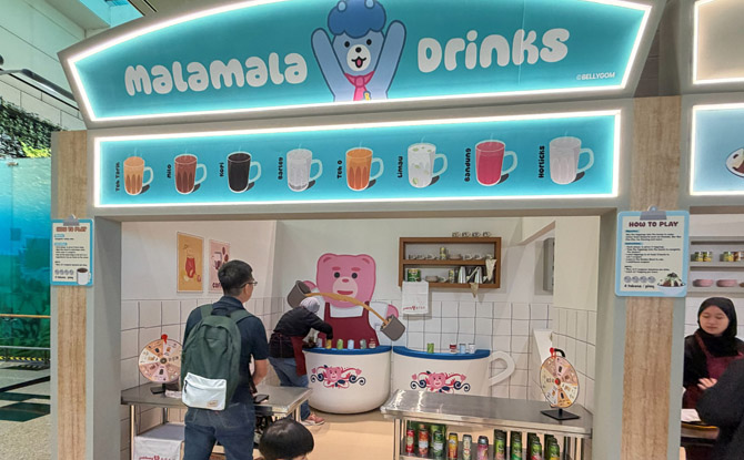 Bellygom Goes Local At Changi Airport: Singapore Adventure With The Pink Bear From 13 Mar To 3 May 3 topple drink tins at the Malamala Drinks stall