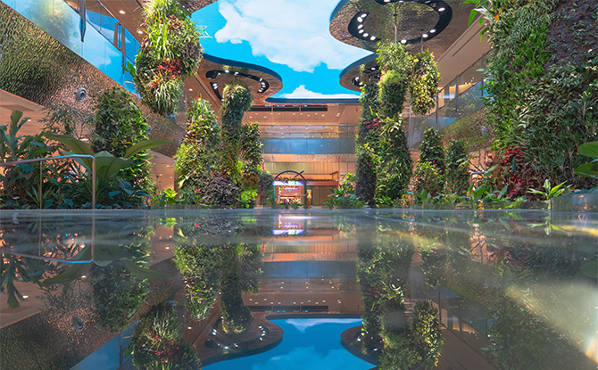is an area filled with landscaped plants with a "digital sky" above that changes