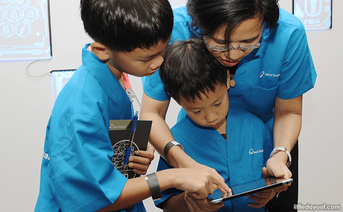 (Clockwise from left) Joshua Cheong, Samuel Cheong, and their mum Kimberly Quek work together to identify the patient’s symptoms.