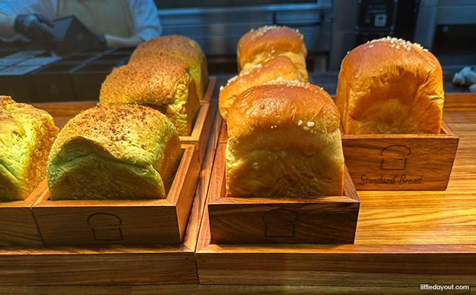 loaves of breads are presented in individual, square wooden boxes